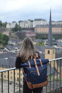 Rear view of woman with umbrella in city against sky