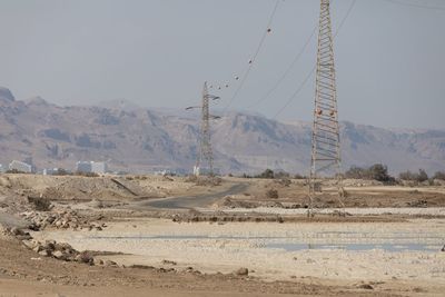 Electricity pylon on land against sky