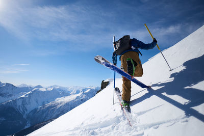 Ski tourer doing an uphill kick turn with mountain backdrop