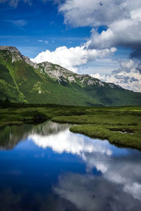 Scenic view of lake by mountains against sky