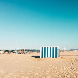 Lifeguard hut on beach against blue sky