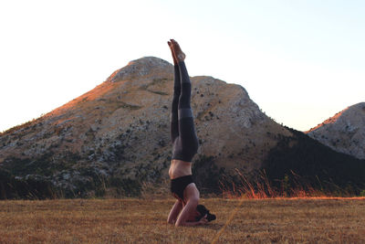 Low section of woman on mountain against clear sky