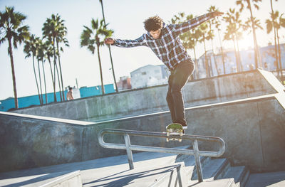 Man jumping on skateboard against trees