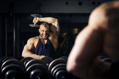 Close-up of muscular man holding dumbbell at gym