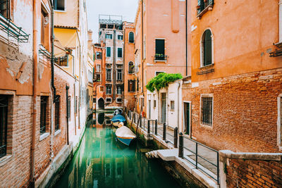 Gondolas moored in canal amidst buildings