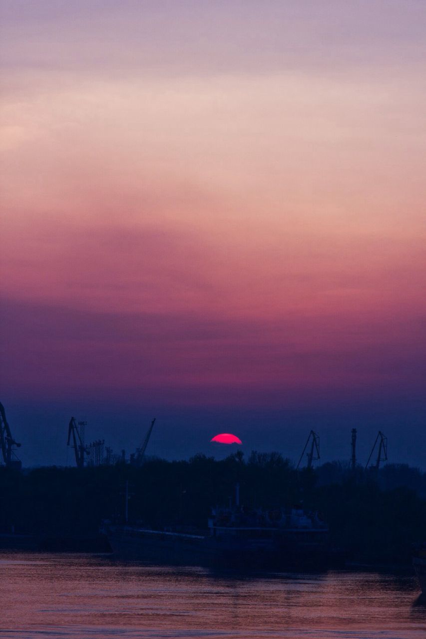 sunset, silhouette, crane - construction machinery, cloud, scenics, tranquil scene, water, sky, tranquility, sea, calm, ocean, development, outline, orange color, crane, waterfront, beauty in nature, dramatic sky, nature, majestic, harbor, romantic sky, sun, outdoors, cloud - sky, no people, moody sky