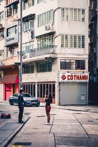 People walking on sidewalk by building in city