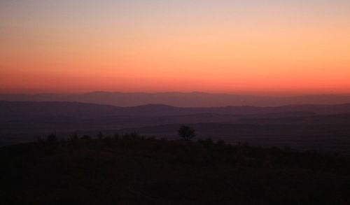 Scenic view of silhouette landscape against orange sky