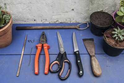 High angle view of gardening equipment amidst potted plants