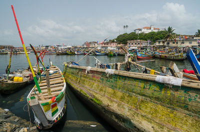 Boats moored at harbor against sky