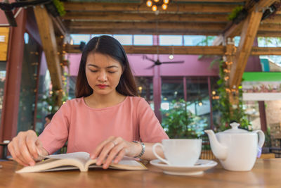 Young woman using mobile phone at table