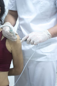 Midsection of doctor holding monitoring equipment and syringe on patient