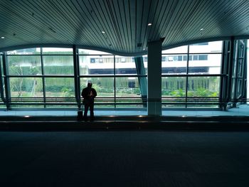 Rear view of silhouette man walking on airport window