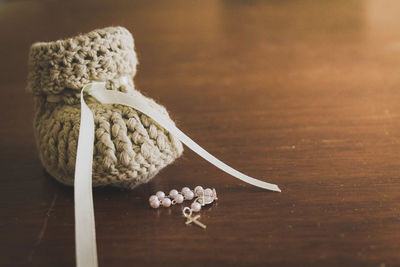 Close-up of knitted baby bootie with rosary beads on table