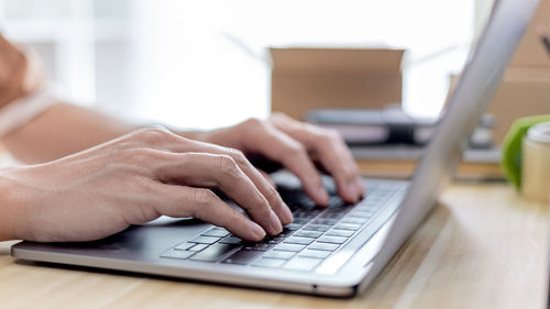 Cropped hands using laptop on table