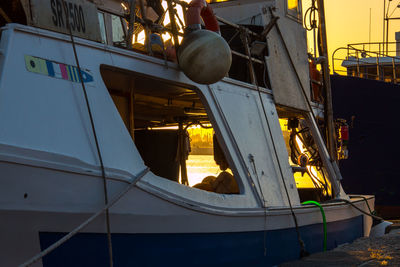 Sailboats moored at harbor during sunset