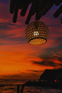 Low angle view of silhouette hanging by sea against sky during sunset