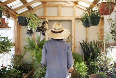 Rear view of woman standing by potted plants