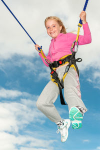 Low angle view of woman holding rope against sky