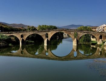 Arch bridge over river against clear sky