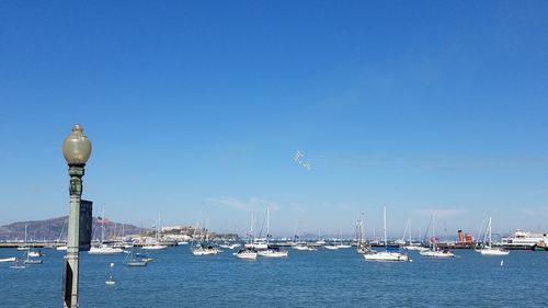 Boats in sea against clear blue sky