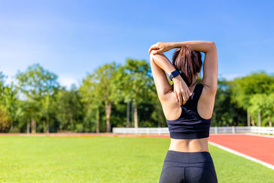 Midsection of woman standing by plants against sky