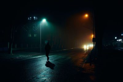 Man walking on illuminated road at night