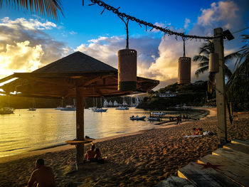 People sitting on beach against sky during sunset