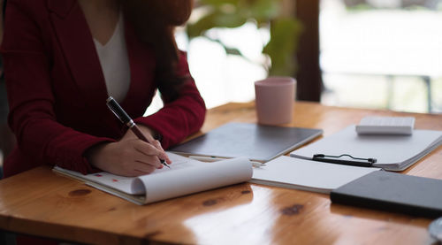 Midsection of woman sitting on table