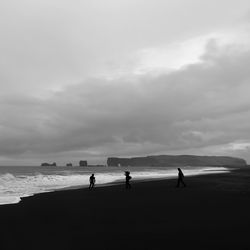 Silhouette people standing on beach against sky