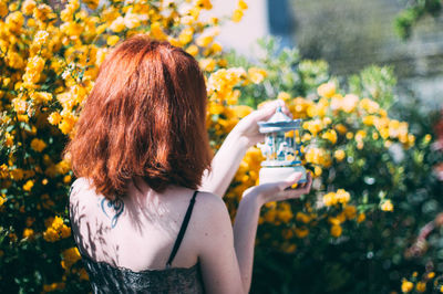 Rear view of woman holding decor by flowers