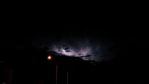 Low angle view of illuminated street lights against sky at night