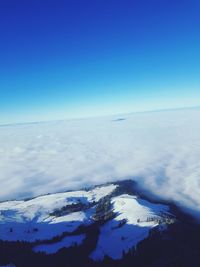 Aerial view of snow covered landscape against blue sky