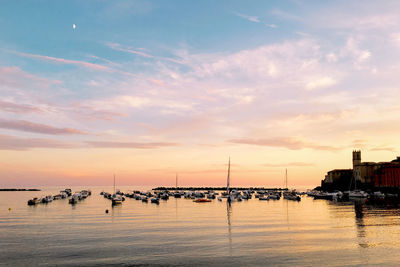 Sailboats moored in marina at sunset