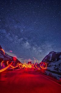 Light trails on road against sky at night