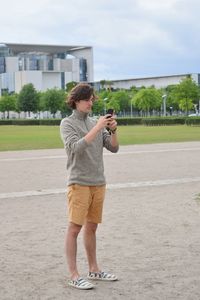 Full length of young man using mobile phone while standing on land