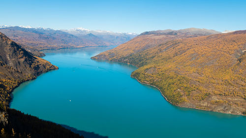 Scenic view of lake and mountains against clear blue sky