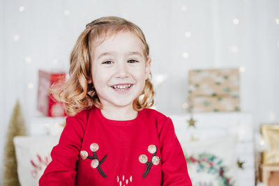 Portrait of happy little girl wearing red christmas dress at home over christmas decoration. holiday