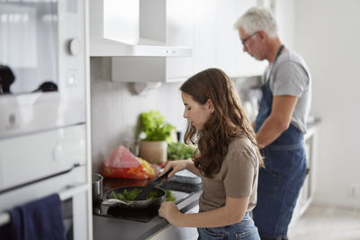 Father and daughter preparing food in kitchen