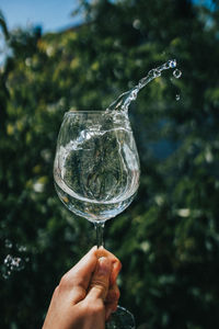 Hand holding wineglass with water splashes
