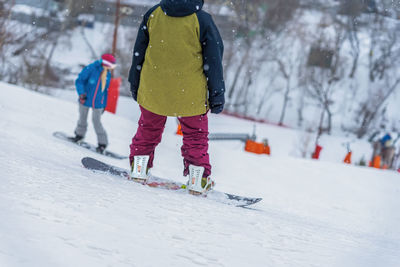 Rear view of boy standing on snowboard