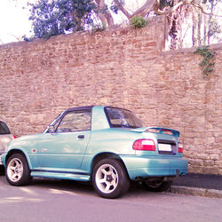 Vintage car on street against brick wall