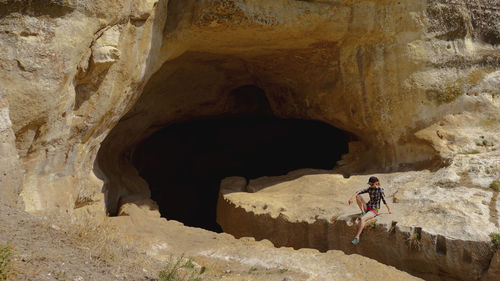 Woman sitting at cave entrance