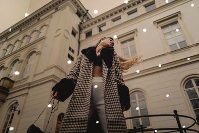 Digital composite image of young woman standing against building