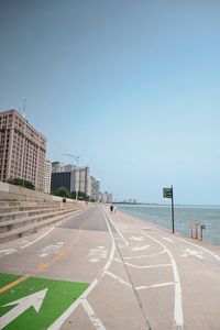 Road by sea against clear blue sky