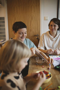 Mothers and daughter making bead jewelry at home