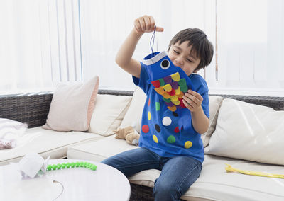 Boy playing with toy on sofa at home