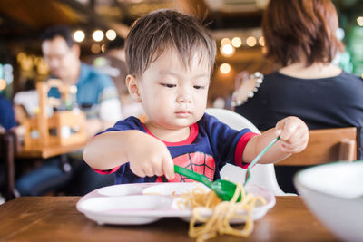 Close-up of boy eating noodles on table at restaurant