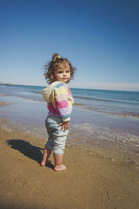 Portrait of girl standing at beach against clear sky