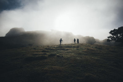 People walking on field against sky